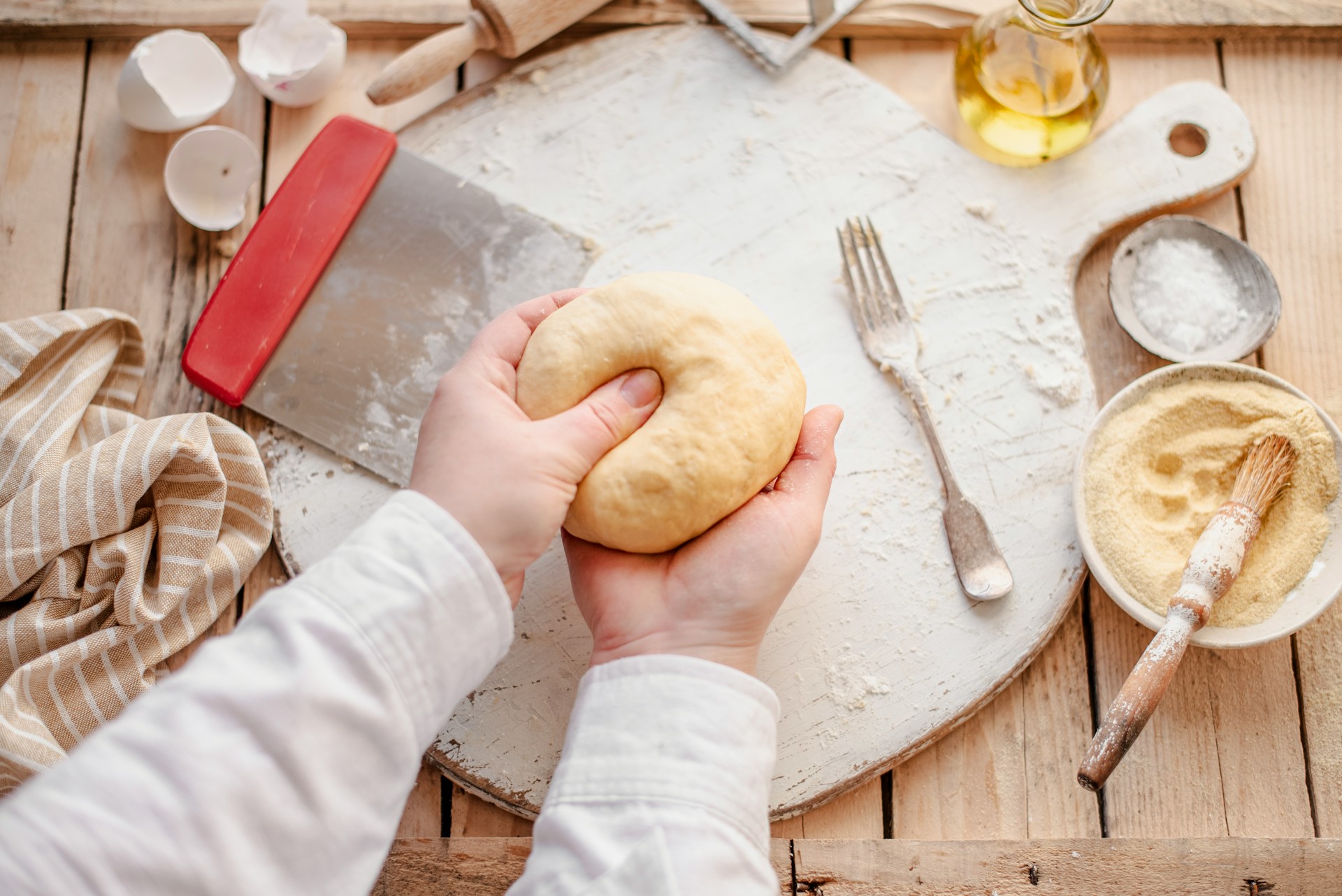 Overhead view of a cottage baker kneading dough in a cozy home kitchen, showcasing artisanal baking techniques.